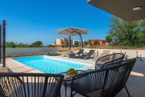 una piscina con sedie e un ombrellone di Villa Esmeralda One by Briskva a Novigrad Istria