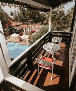 uma varanda com mesa e cadeiras e uma piscina em The Regalia Resort em Mandrem