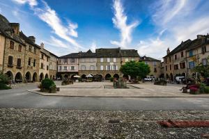 a street in a city with buildings and a blue sky at Hôtel-restaurant Le Sénéchal in Sauveterre-de-Rouergue