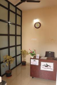 una sala de espera con un reloj en la pared y plantas en Happy holiday Inn en Chikmagalūr