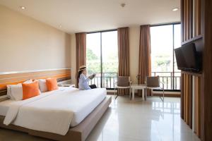 una mujer sentada en una cama en una habitación de hotel en Imm Hotel Thaphae Chiang Mai en Chiang Mai