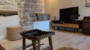 een woonkamer met een flatscreen-tv en een kruk bij Cal Rei in Grañena de Cervera