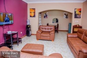 a living room with brown leather furniture and pink walls at Villa Daci in Gulu