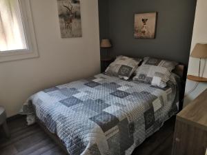 ein Schlafzimmer mit einem Bett mit einer Decke darauf in der Unterkunft Gîte Grandeur Nature in Saint-Aignan
