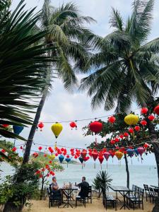 two people sitting at tables on the beach with colorful lanterns at Bãi Xếp Beach in Quy Nhon