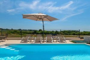 una piscina con ombrellone e sedie e un tavolo con ombrellone di Villa Esmeralda Two by Briskva a Novigrad Istria