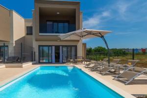 una piscina con sedie e ombrellone accanto a una casa di Villa Esmeralda Two by Briskva a Novigrad Istria