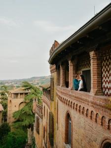 two people sitting on a window ledge of a building at Cora Aparthotel Stradivari in CastellʼArquato