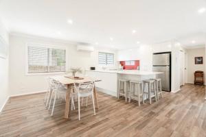a kitchen with a table and chairs in a room at Loulu in Pearl Beach +3 photos