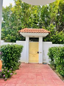 a yellow door in a white wall with a tile roof at Villa richement meublée Ennacer 89€/j in Ariana