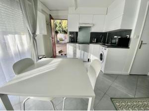 a white kitchen with a white table and chairs at Jean Paul 2 Au cœur de Rouen , gare "Ménage & Linge Inclus" in Rouen