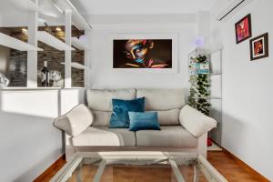 Sala de estar blanca con sofá y almohadas azules en Salome de SteraM Flats Torremolinos, en Torremolinos