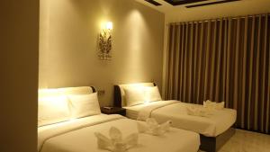 Habitación de hotel con 2 camas con sábanas blancas en Suorsdei Boutique, en Kampot