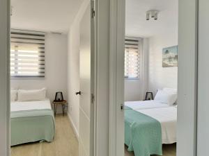 2 Betten in einem Zimmer mit weißen Wänden und Fenstern in der Unterkunft Apartamento Bonita Vista in Vinarós + 23 Fotos