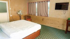 a bedroom with a bed and a fan and a window at 14 miles hotel and restaurant in Kāskī