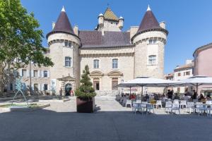 a large building with chairs and umbrellas in front of it at Le Fou - Appt dans le centre dAubenas in Aubenas