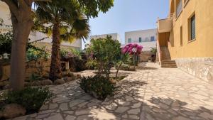 a stone walkway with trees and flowers in front of a building at Marzamemi, Sul Livello del MARE, GOLD in Marzamemi