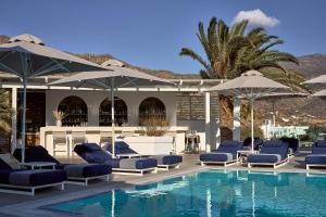 uma piscina com espreguiçadeiras azuis e guarda-sóis em Ios Palace Hotel & Spa em Mylopotas