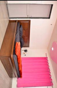 プネにあるJadhav Farmsのピンクのカーペットが敷かれたドミトリールームのベッド1台分です。