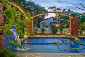 a swimming pool in a garden with an arch over it at STAR HOLIDAY VILLAS in Anjuna