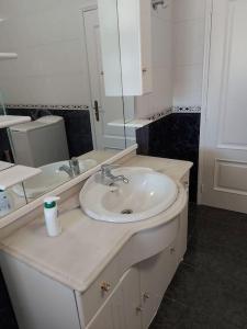 een witte badkamer met een wastafel en een spiegel bij Comfortabel downstairs appartment close to Coimbra in Vila Nova de Poiares