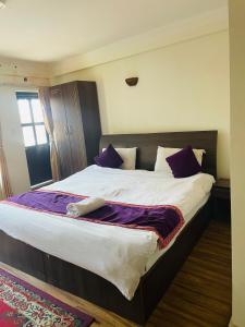 a bedroom with a large bed with purple pillows at Hotel Bhaktapur Inn in Bhaktapur