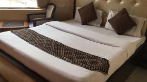 Bett mit weißer Bettwäsche und Kissen in einem Zimmer in der Unterkunft HOTEL ONYX in Zirakpur