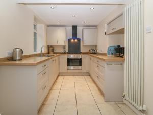 a kitchen with white cabinets and a tile floor at Castell in Pwllheli