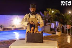 a man is cooking food on a table at StayVista's Ivory Grandeur - Valley-View Villa with Outdoor Pool, Lawn featuring a Gazebo & Machan in Lonavala