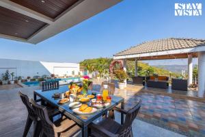 a table with food on it on a patio at StayVista's Ivory Grandeur - Valley-View Villa with Outdoor Pool, Lawn featuring a Gazebo & Machan in Lonavala