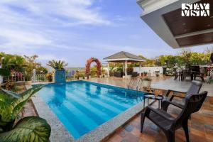 a swimming pool with a table and chairs next to it at StayVista's Ivory Grandeur - Valley-View Villa with Outdoor Pool, Lawn featuring a Gazebo & Machan in Lonavala