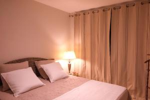 a bedroom with a bed with white sheets and a lamp at Maison d'hôtes Les Oliviers in Cazouls-lès-Béziers