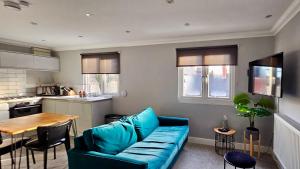 a living room with a blue couch and a kitchen at Victoria House by Switchback Stays in Cardiff