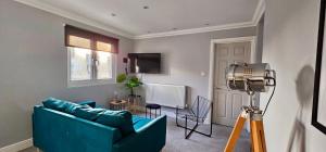 Una sala de estar con un sofá azul y un televisor. en Victoria House by Switchback Stays, en Cardiff