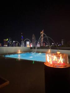 a pool with a fountain with a city in the background at Serene roof A quiet romantic luxurious in Kuwait