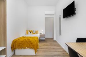 Smart Living Hub: Designer Spaces for Digital Nomads & Remote Workers في لشبونة: غرفة نوم عليها سرير مع بطانية صفراء