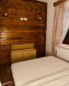 1 dormitorio con 1 cama y pared de madera en Cabana Bogdi, en Borşa