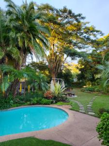 a swimming pool in a yard with palm trees at Mijn Kitchen Coffee Shop and B&B in Blantyre