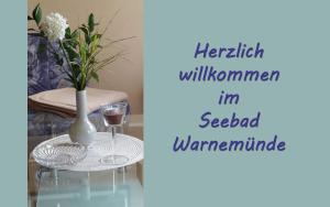 ヴァーネミュンデにあるFerienwohnung Ostsee_Gru_ _ Objektの花瓶とワイン1杯