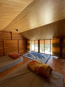 two beds in a room with wooden walls at Chú Ba Farmstay - cách Đà Lạt 40km in Ấp Phú Thuận