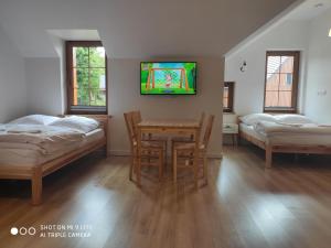 Habitación con 2 camas, mesa y TV. en Szklarska Chata, en Szklarska Poręba