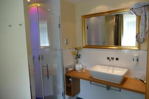 La salle de bains est pourvue d'un lavabo et d'une douche avec un miroir. dans l'établissement Hotel Heide Kröpke, à Essel