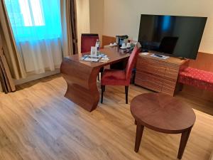 a room with a desk with a chair and a television at Hotel Heide Kröpke in Essel