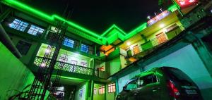 a green and white building with a car parked in front at Lamin Guest House in Dawki