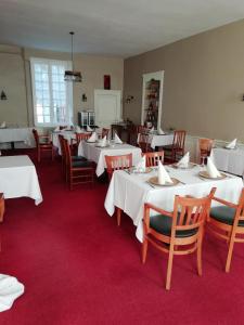 un comedor con mesas y sillas blancas en Hôtel du Berry, en Aigurande