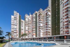 uma fila de edifícios de apartamentos altos com uma piscina em Primera línea de playa em Alicante