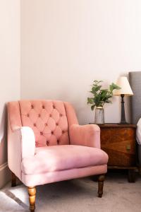 Kent的住宿－Lewknor Lodge: Stunning 5 bed, 4 bathroom house in Ramsgate，一张粉红色的椅子,坐在桌子旁,边边有台灯
