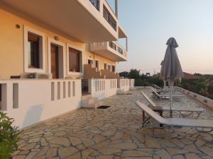 a patio with chairs and an umbrella on a building at Aktaion Apartments in Samothraki