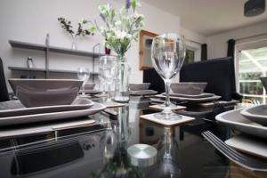 a dining table with plates and wine glasses on it at The Lockett by StayStaycations in Plymouth