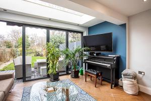 倫敦的住宿－Modern and Spacious Colliers Wood Home，客厅配有钢琴和蓝色的墙壁